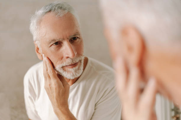 istock Senior man looking at reflection and touching face, skin care concept 2170643739