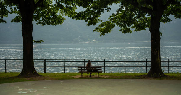 Borbino, Italy - Woman sitting on the bench and looking to Como lake.