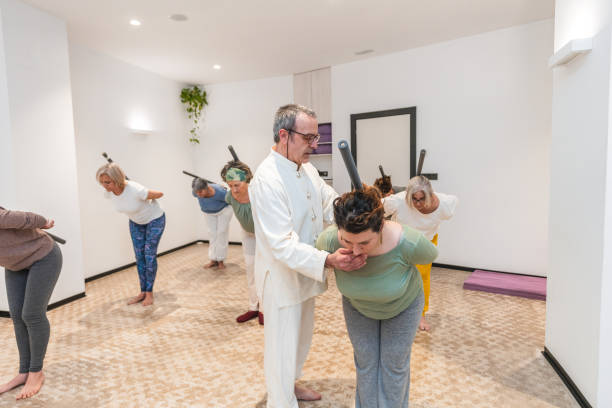 istock A group of people are practicing yoga in a room with a man teaching them 2170651526