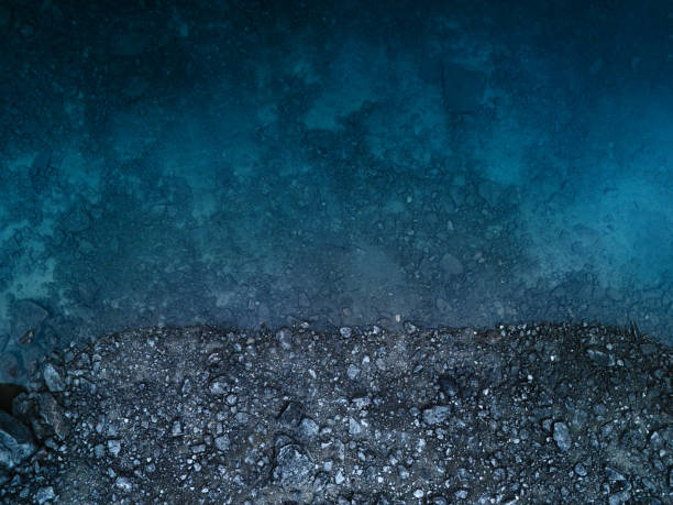 Beautiful blue lake surface and dark grey rocks. Stunning dramatic scenery, directly above view. Natural abstract wallpaper