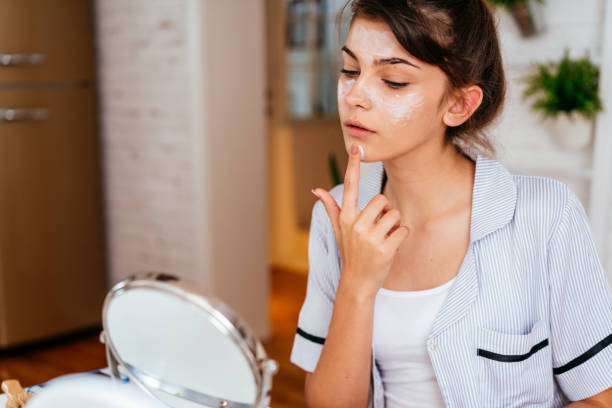 istock Young woman applying moisturizer cream on her face 2170656125