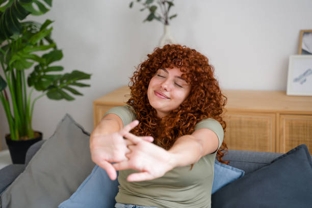 istock Young woman stretching arms while relaxing on sofa at home 2170656147