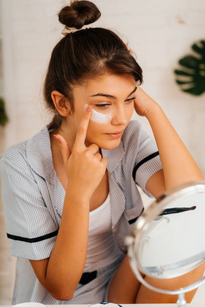 istock Young woman applying moisturizer cream on her face 2170656149
