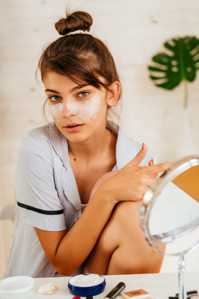 istock Young woman applying moisturizer cream on her face 2170656164
