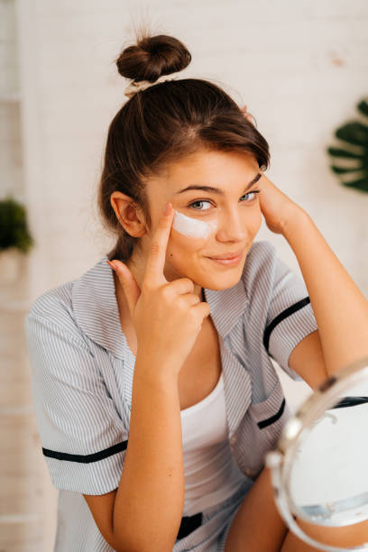 istock Young woman applying moisturizer cream on her face 2170656208