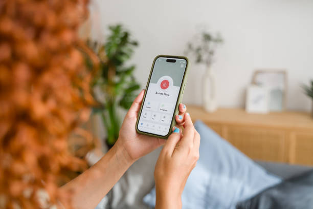 istock Woman activating home security system on smartphone app while relaxing at home 2170656243