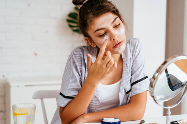 istock Young woman applying moisturizer cream on her face 2170656268