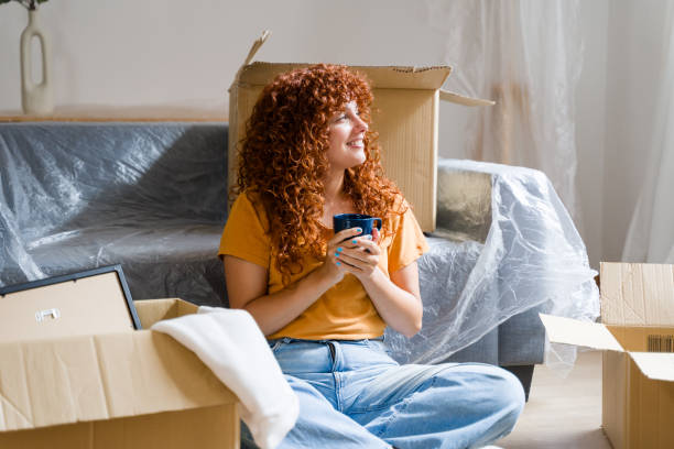 istock Woman taking a break from unpacking and drinking coffee in new home 2170657144