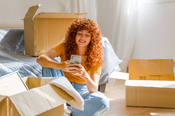 istock Happy woman using smartphone and relaxing during break from moving house 2170657166