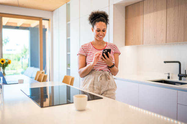 istock Mixed Race Woman Enjoying Phone Time in Modern Kitchen 2170658614