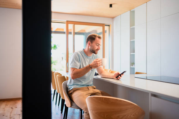 istock Caucasian Man Relaxes with Coffee and Mobile Device in Kitchen 2170658618