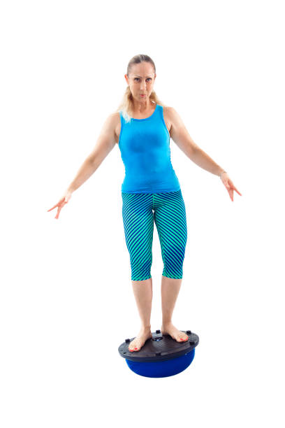 Determined woman balancing on a Bosu ball, focusing on stability, core strength, and coordination, isolated on a white background.
