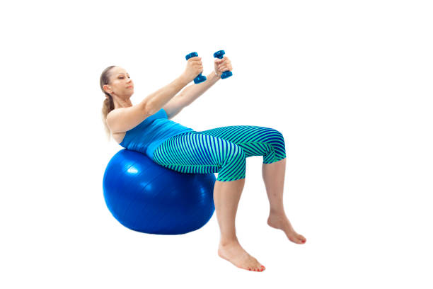 Focused woman using dumbbells while reclining on a stability ball, targeting core strength, balance, and upper body, isolated on a white background.