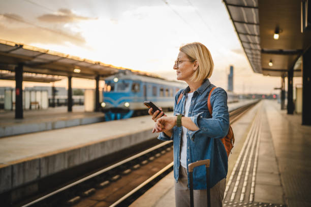 istock Mature woman wait for the train, use cellphone and walk with suitcase 2170659005