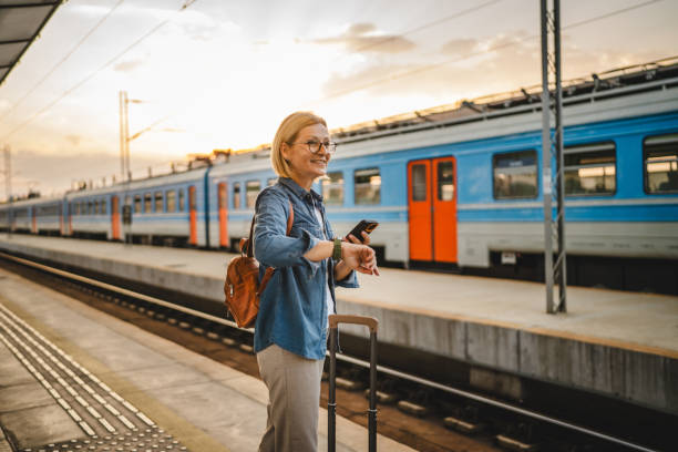 istock Mature woman wait for the train, use cellphone and walk with suitcase 2170659088