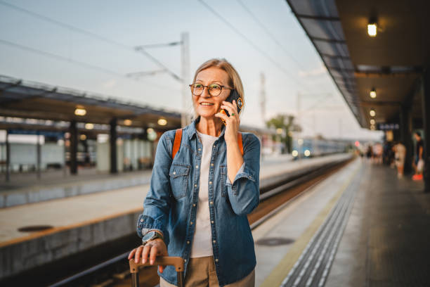 istock Mature woman wait for the train and talk on mobile phone during wait 2170659351