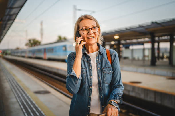 istock Mature woman wait for the train and talk on mobile phone during wait 2170659353