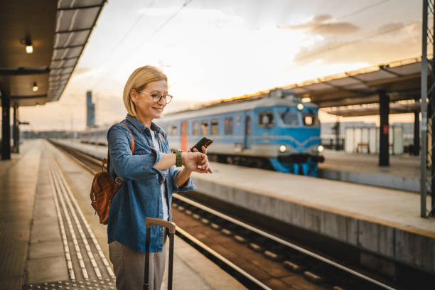 istock Mature woman wait for the train, use cellphone and walk with suitcase 2170659972
