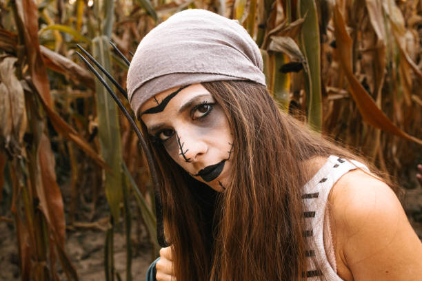 Close up of a woman in Halloween costume standing in cornfield with pitchfork