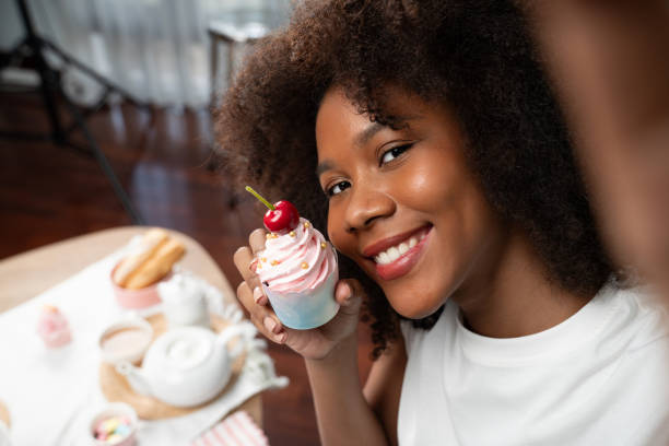 istock African blogger presenting cupcake with selfie on smartphone. Tastemaker. 2170663352