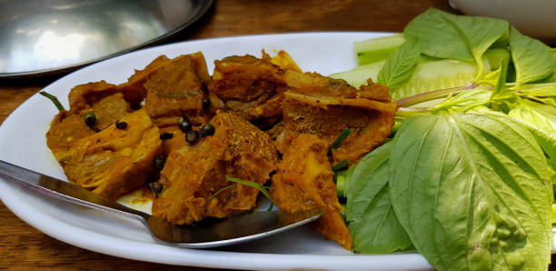 istock Spicy stir fired pork cartilage bone with yellow curry and vegetable, Basil leave, Sliced cucumber and Green Lettuce on white plate at Thai restaurant. Thai local and Asian food concept. 2170663586