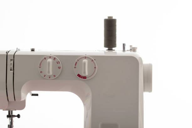 istock Part of a sewing machine with a black spool of thread against a white wall. Tailoring service concept. Copy space for text, automatical 2170667672