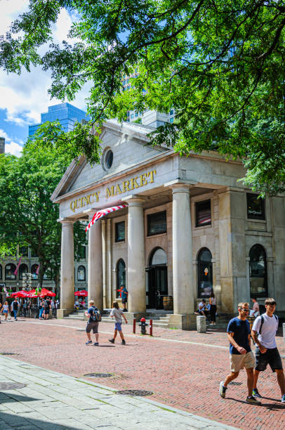 Boston, Massachusetts, USA -August 12, 2024- Tourists roam in and around the entrance of historic Quincy Market, a major Boston tourist attraction on a beautiful summer morning.