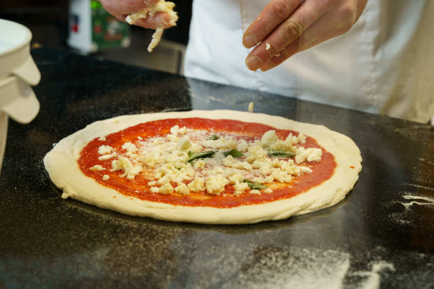 istock A chef preparing a pizza with tomato sauce and spreading mozzarella cheese on pizza 2170683428