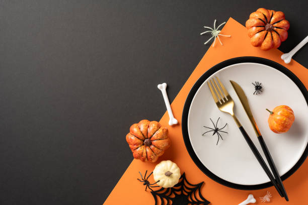 istock Festive Halloween table setting with pumpkins, spiders, bones, and a place setting on an orange background 2170688152