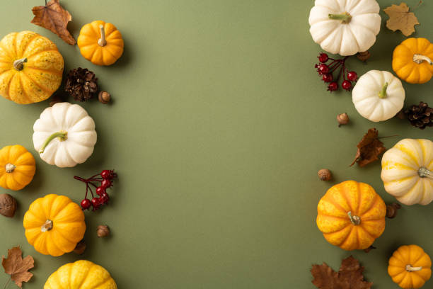istock Decorative autumn arrangement featuring pumpkins, fall leaves, and berries on a green backdrop for seasonal and Thanksgiving themes 2170688220