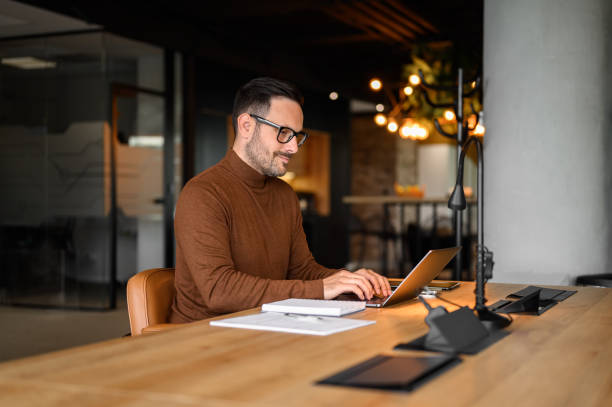 istock Focused male financial advisor in glasses analyzing report over laptop while working at desk in office 2170700215