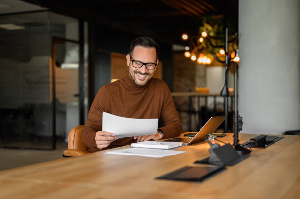 istock Confident young businessman auditing revenue report and planning budget while working at desk in office 2170700228