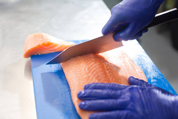 istock Chef cutting salmon fillet with sharp knife on blue cutting board 2170702513