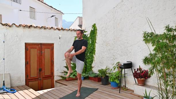 istock Man practicing yoga on rooftop deck surrounded by plants and charming architecture, promoting relaxation, fitness, and mindfulness in an outdoor setting. 2170723624
