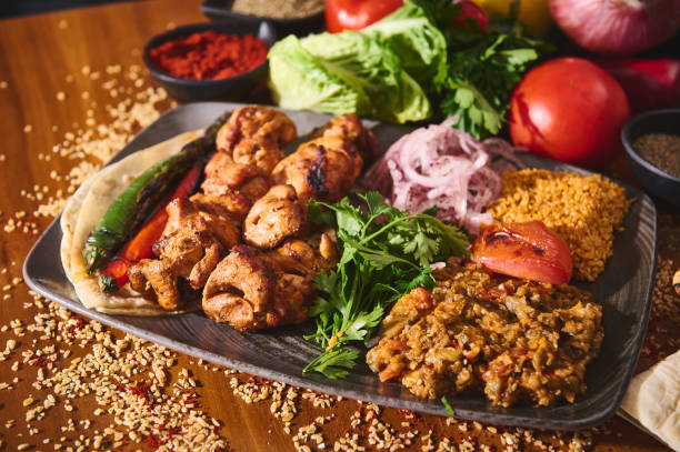 Delicious Turkish kebab platter with grilled chicken, fresh vegetables, and flavorful rice, garnished with herbs on a rustic wooden table, perfect for a vibrant Middle Eastern dining experience