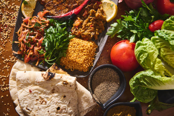istock Delicious Mediterranean feast featuring grilled meat, fresh herbs, tomatoes, spices, rice, and flatbread on wooden table 2170732491