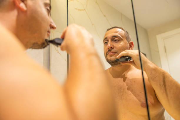 istock Oversized man standing in the bathroom and shaving his beard using an electric shaver. 2170734024