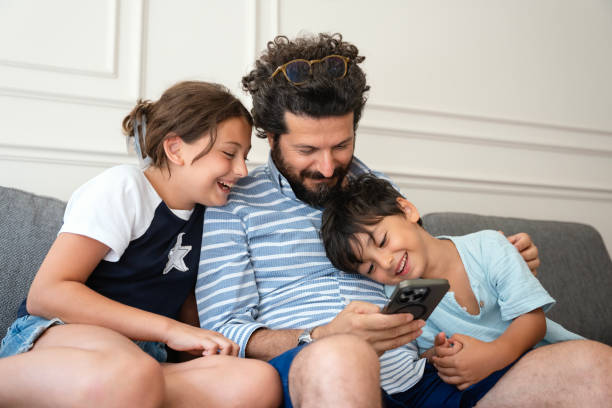 istock Kids with father using a mobile phone together at home 2170738468