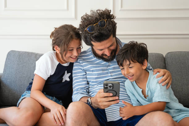 istock Kids with father using a mobile phone together at home 2170738513