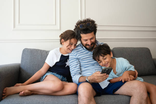 istock Kids with father using a mobile phone together at home 2170738552