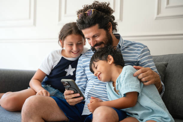 istock Kids with father using a mobile phone together at home 2170738554
