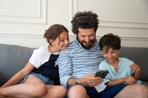 istock Kids with father using a mobile phone together at home 2170738575