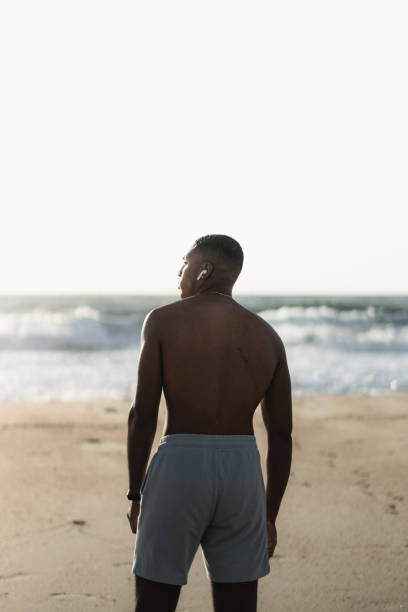 istock Young athletic man wearing earbuds enjoying a day at the beach 2170742615