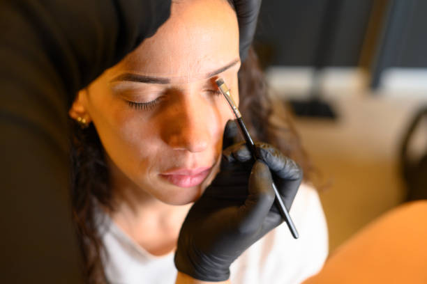 istock Beautician applying makeup to prepare simulation for permanent makeup on eyebrows of latino woman 2170747890