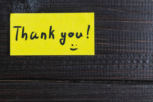 istock A small note with the word thank you on a dark wooden table background 2170748469