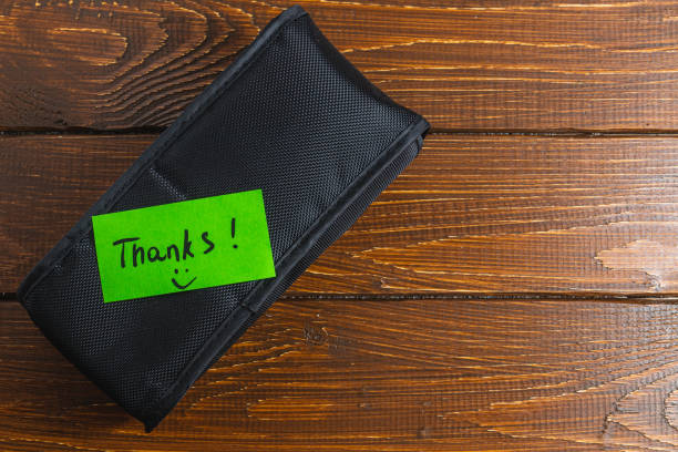 A black box diagonally on a table with a green thank you label and a smiley face High quality photo