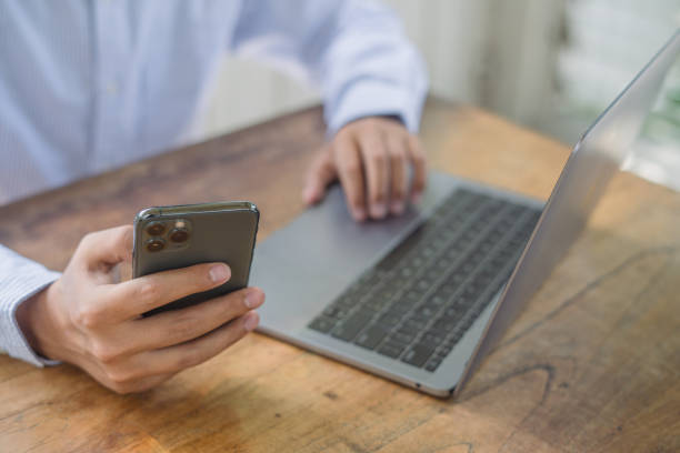 istock Work from home. Casual business man using mobile phone during online working on laptop computer from home office 2170764673