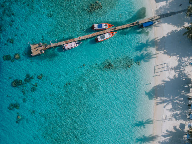 Drone point of view anchored boats at lagoon with pier in lang tengah island, malaysia Drone point of view anchored boats at lagoon with pier in lang tengah island, malaysia malaysia island stock pictures, royalty-free photos & images
