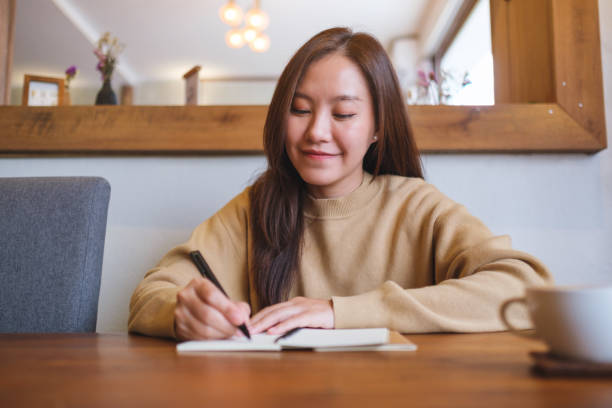 istock Portrait image of a young woman writing on a notebook on the table 2170772384