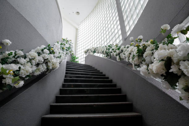 View of an interior staircase from below, decorated with white flowers on both sides. Wedding concept.
